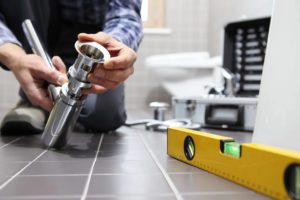 man working on plumbing with level